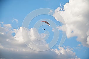 Sunny bright blue sky background with white clouds in summer. Paragliding extreme sport in the rural mountain area. Lonely