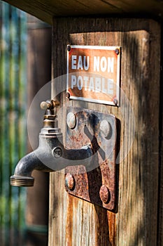 Sunny closeup of rusted faucet with non drinkable warning water photo