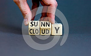 Sunny or cloudy symbol. Concept word Sunny or Cloudy on wooden cubes. Beautiful grey table grey background. Businessman hand.