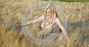 Sunny composition. Happy blonde girl with natural make-up and lovely smile is hugging the high golden spikes of wheats
