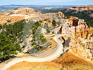 Sunny day in Bryce Canyon, Utah, USA. Dusty country road in rocky valley with green trees