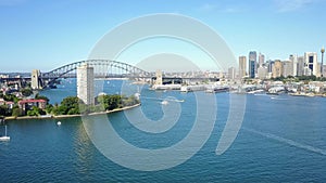 Sunny day flying over the Sydney bay with a view of boats, vessels and the Harbor Bridge