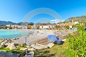 A sunny day on the French Riviera as they relax on the sandy Plage de Fossan Mediterranean beach in Menton, France