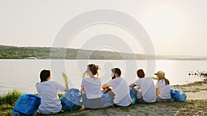 In a sunny day group of multiethnic volunteers have a break time after they finish to clean all the rubbish they giving