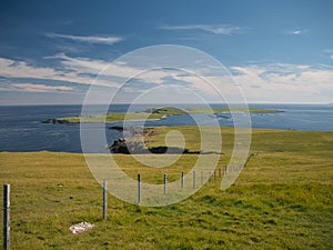 On a sunny day with light clouds, the island of Balta from the Keen of Hamar near Baltasound on the island of Unst in Shetland