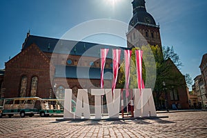 Sunny day in Riga, Latvia with LATVIA letters in front, flag colors.