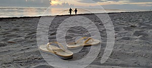 Sunny day, sandals on the sand. Lovely couple