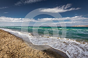 Sunny day on sandy Alikes beach near Tigaki with dramatic cloudy sky. Island of Kalymnos in background. Island of Kos, Greece