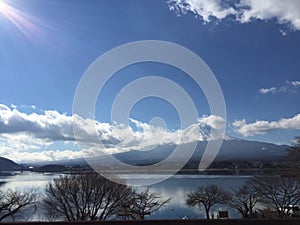 Sunny day view of Mt. Fuji with clear blue sky, clouds and smooth lake surface in winter, Kawaguchiko, Yamanashi, Japan