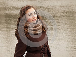 Sunny girl in coat with small lake on the back
