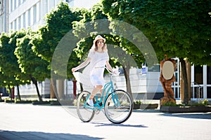 Sunny girl riding in sun on blue retro bicycle