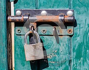 Sunny green blue wooden door with rusted lock for colors