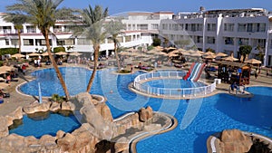 Sunny hotel resort with luxury blue swimming pool, beach umbrellas and sunbeds in Egypt