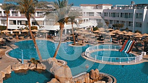 Sunny hotel resort with luxury blue swimming pool, beach umbrellas and sunbeds in Egypt