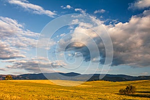 Sunny landscape with mountains and blue sky with clouds .