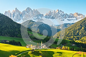 Sunny landscape with Santa Magdalena village against the Geisler mountains covered with snow at sunrise, Val Di Funes in