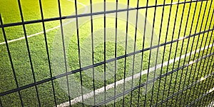 Sunny lawn field for playing minifootball behind the green fence mesh, sport background