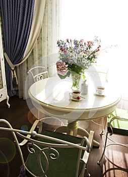 Sunny living room with big bouquet on round table, interior in P