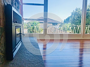 A sunny living room with fireplace. French windows and balcony outside, interior design.