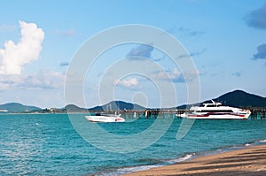 Sunny Maenam beach of Koh Samui, pier with boats Thailand