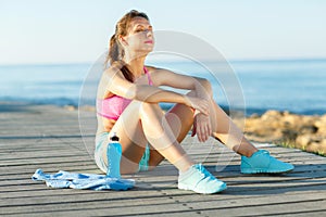 Sunny morning on the beach, athletic woman resting after running