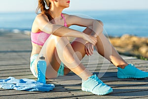 Sunny morning on the beach, athletic woman resting after running