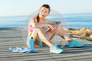 Sunny morning on the beach, athletic woman resting after running