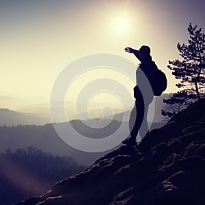 Sunny morning. Hiker is standing on the peak of rock in rock empires park and watch over misty and foggy morning valley photo