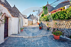 Sunny morning view of strret with trullo trulli -  traditional Apulian dry stone hut with a conical roof. Bright spring cityscap