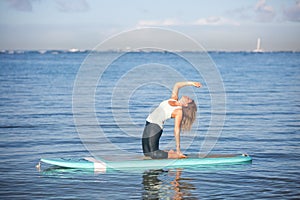 Sunny morning work out a pretty young woman in SUP Yoga back ben