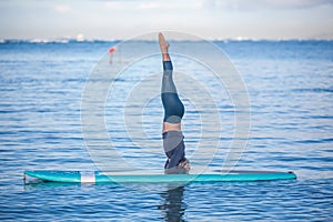 Sunny morning work out a pretty young woman in SUP Yoga practice photo