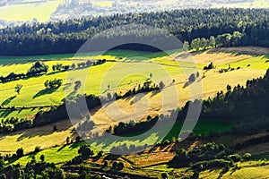 Sunny mountain valley with green fields and meadows. Scenic farmland landscape aerial view.