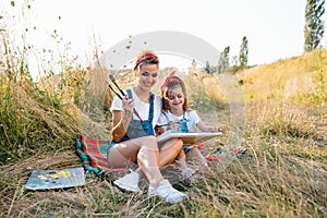 Sunny nature, mom and daughter paint a picture in a park , painting a Little Child, Child Creativity. Mother& x27;s Day.