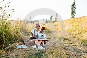 Sunny nature, mom and daughter paint a picture in a park , painting a Little Child, Child Creativity. Mother's Day.