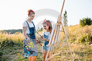 Sunny nature, mom and daughter paint a picture in a park , painting a Little Child, Child Creativity. Mother's Day.
