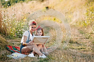 Sunny nature, mom and daughter paint a picture in a park , painting a Little Child, Child Creativity. Mother& x27;s Day.