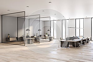 Sunny open space office room with workspaces divided by glass partitions, city view from high floor and light walls and ceiling