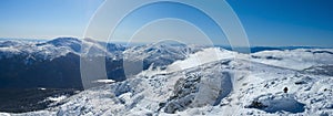 sunny panoramic view of snowy mountain range with people walking along it photo