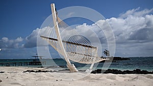 Sunny paradise white sand beach with traditional braided hammock.