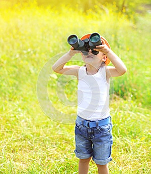Sunny photo child boy looks in binoculars outdoors in summer
