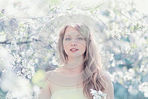 Sunny portrait of a beautiful woman in a flowering spring