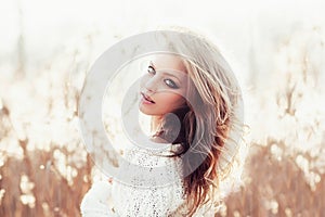 Sunny portrait of a beautiful young blonde girl in a field in white pullover, the concept of health and beauty