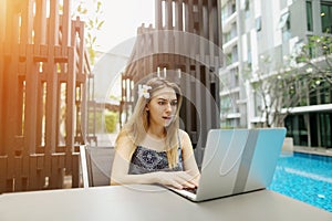 Sunny portrait of girl with flower and laptop near pool.