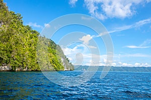 Sunny Rocky Shores with Rainforest and Yacht in the Distance