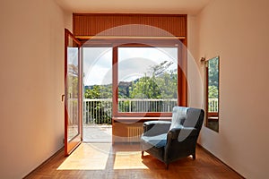 Sunny room interior with open window and blue velvet armchair in country house