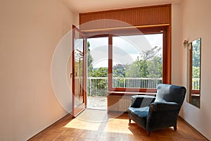 Sunny room interior with terrace and blue velvet armchair in country house