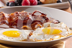 Sunny side up eggs with fried bacon. photo