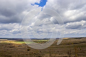 Sunny spring landscape yellow fields with black faded spots, blue cloudy sky fields. Russia countryside rural landscape