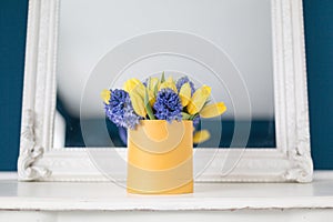 Sunny spring morning. Bunch of blue hyacinths and yellow tulips on white table. Present for a girl. Flowers bouquet in