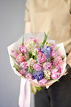 Sunny spring morning. Young happy woman holding a beautiful bunch of hyacinths and tulips in her hands. Present for a